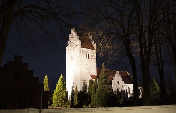 Hvid lansbykirke med lys på