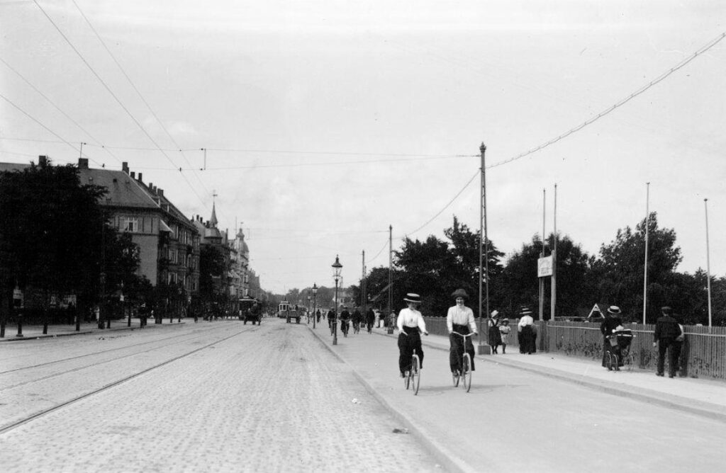 Cykelsti på Strandvejen med to kvindelige cyklister i cykelkjoler, hvide bliser og stråhatte